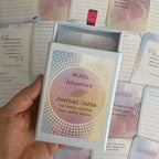 Midlife Adventure Journal Cards – open deck box held in hand for women unlocking their midlife wisdom, with reminder and prompt cards visible in the background