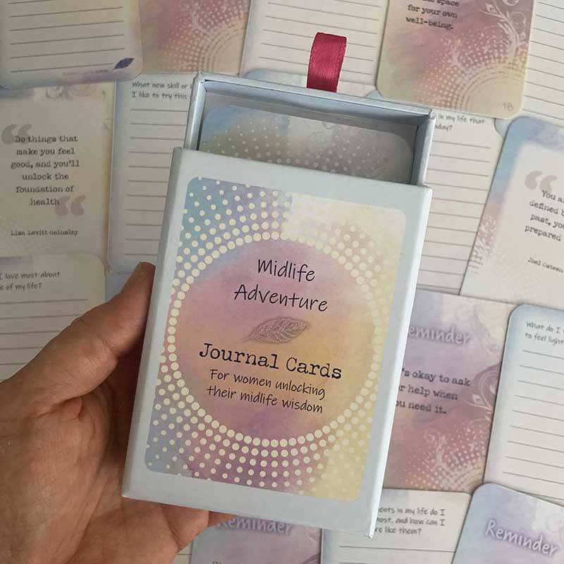 Midlife Adventure Journal Cards – open deck box held in hand for women unlocking their midlife wisdom, with reminder and prompt cards visible in the background