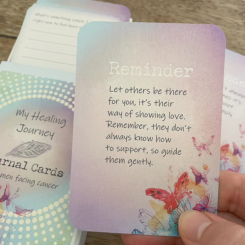 My Healing Journey Journal Cards – close-up of a reminder card reading "Let others be there for you, it's their way of showing love," held beside the deck box and lined journal cards.